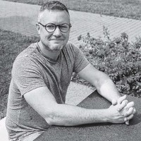 black and white photo of michael arfken sitting at the table with his fingers interlaced